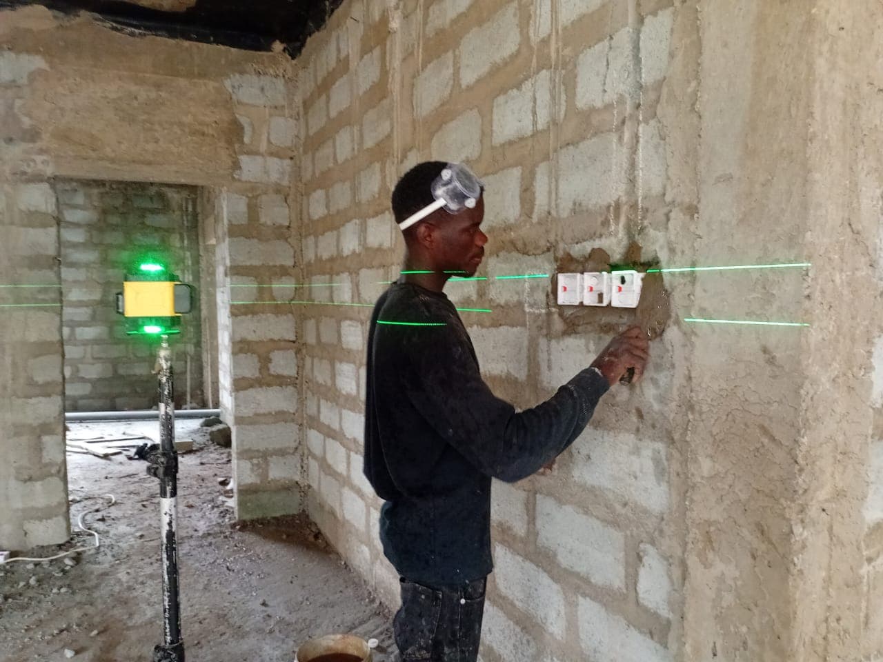 Lead electrician setting out socket positions with a laser level before installation